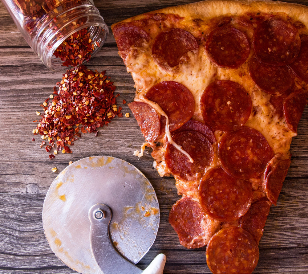 Brother Bruno pepperoni pizza slice with red pepper flakes and pizza cutter